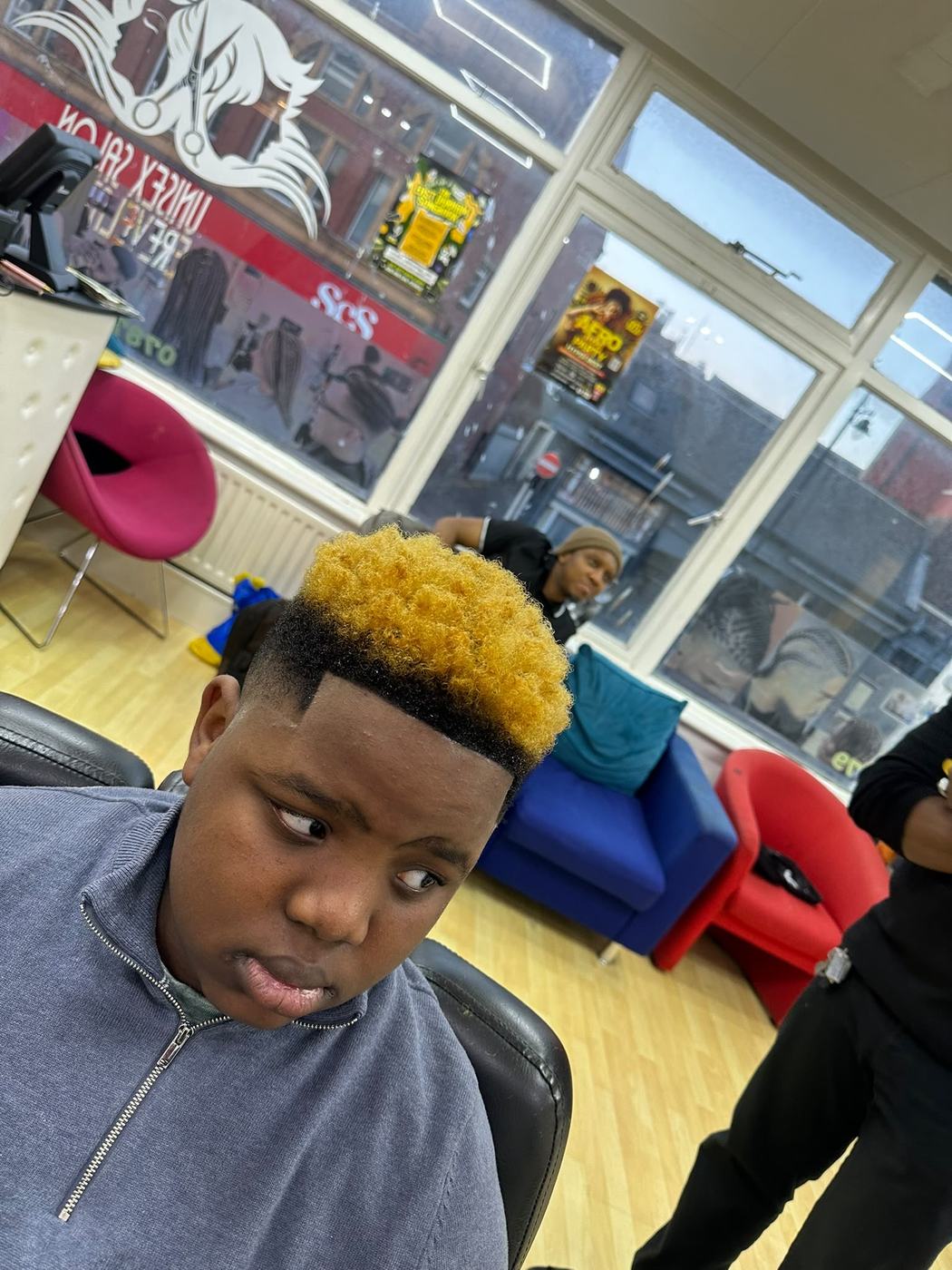 Bold blonde tint on a curly top fade